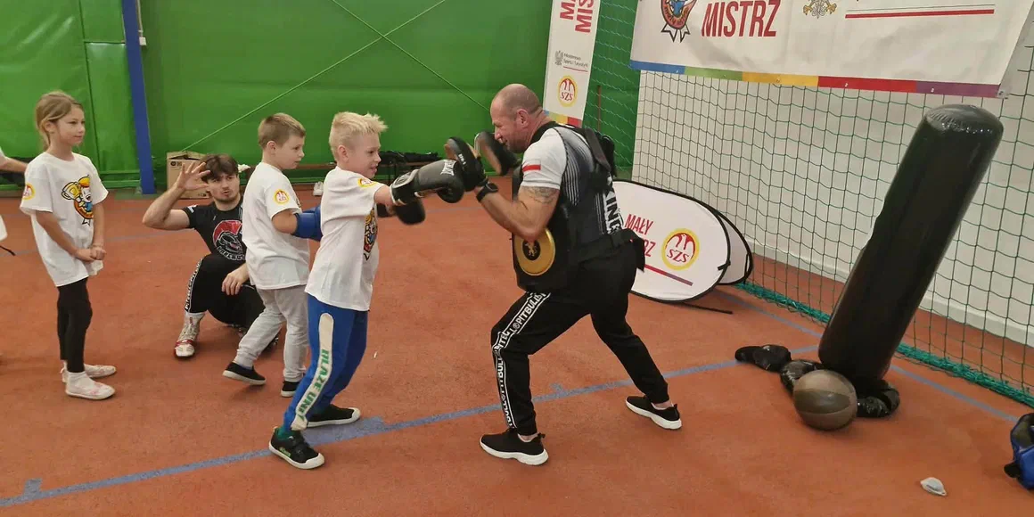 Trener prowadzi ćwiczenia z dziećmi na sali sportowej