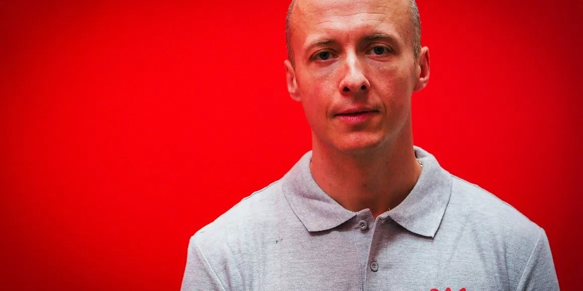 Marcin Smolarczyk na portretowym zdjęciu na czerwonym tle
